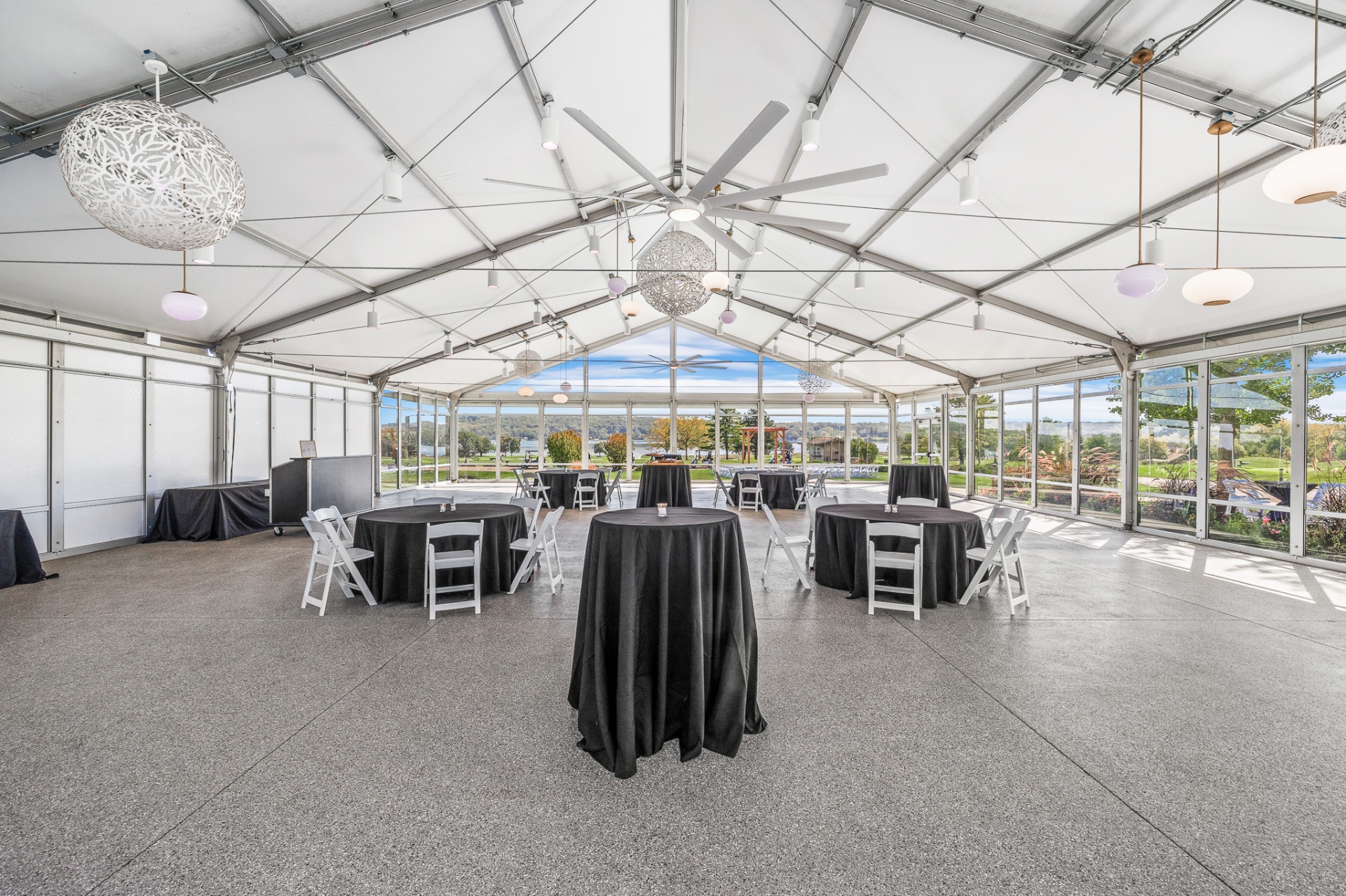 Lakeside event pavilion set with cocktail tables and panoramic water views